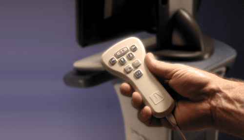 Hand holding the handheld controller for the intravascular thermography system showing buttons and ergonomic grip.