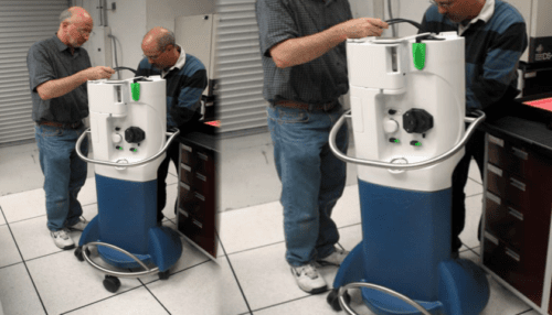 Two technicians inspecting the assembled intravascular thermography diagnostic system on a wheeled cart in a lab setting.